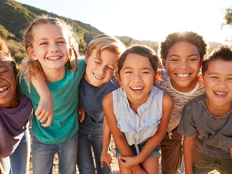 A group of children posing together outdoors with smiles on their faces.
